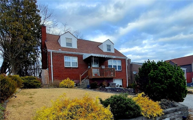 view of front facade with brick siding, a chimney, a front lawn, and roof with shingles