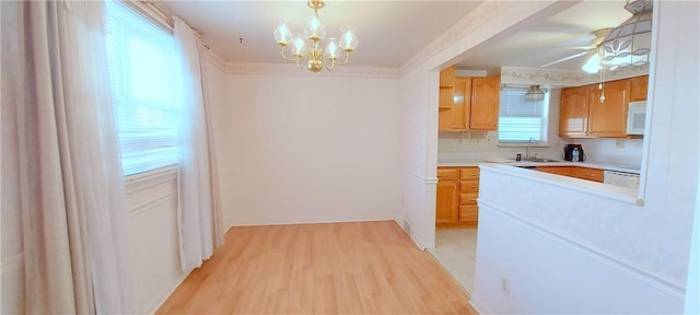 kitchen featuring crown molding, light countertops, light wood-type flooring, white appliances, and ceiling fan with notable chandelier