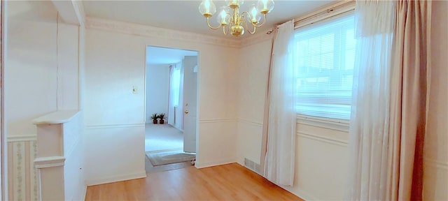 hall featuring an inviting chandelier, light wood-style flooring, and crown molding