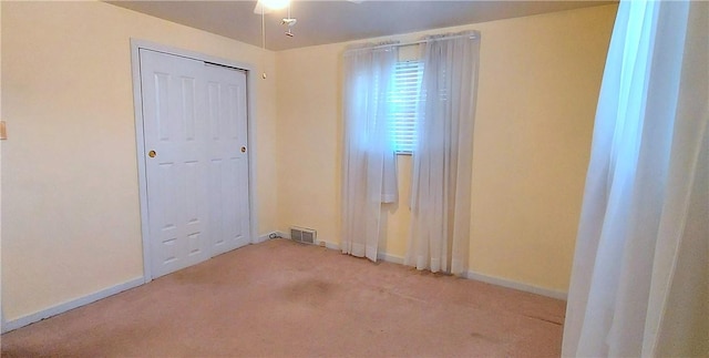 spare room featuring carpet floors, visible vents, and baseboards