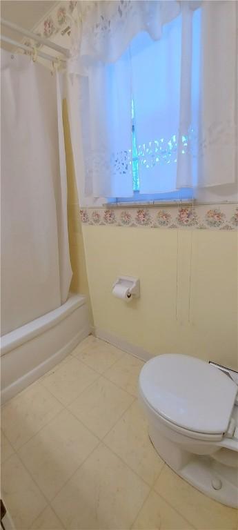 full bath featuring toilet, shower / tub combo, and tile patterned floors