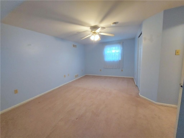 spare room featuring baseboards, visible vents, a ceiling fan, and light colored carpet