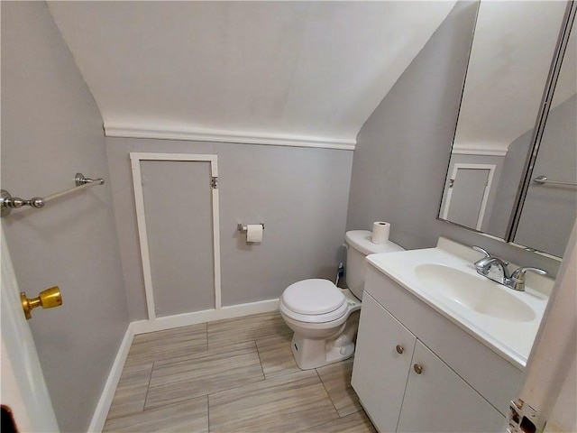 bathroom featuring toilet, lofted ceiling, baseboards, and vanity