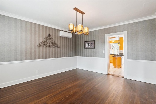 unfurnished room with wallpapered walls, a wall unit AC, ornamental molding, a notable chandelier, and dark wood-style flooring