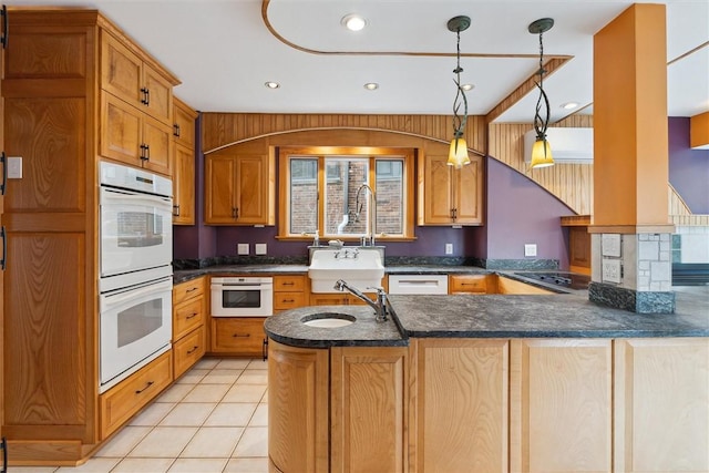 kitchen featuring double oven, light tile patterned floors, a peninsula, and a sink