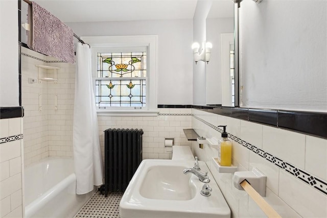 bathroom featuring tile walls, radiator heating unit, shower / bathtub combination with curtain, and a sink