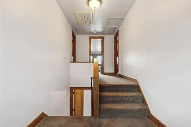 staircase with visible vents, baseboards, and carpet