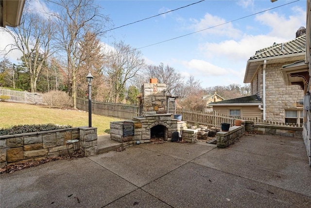 view of patio with an outdoor stone fireplace and a fenced backyard