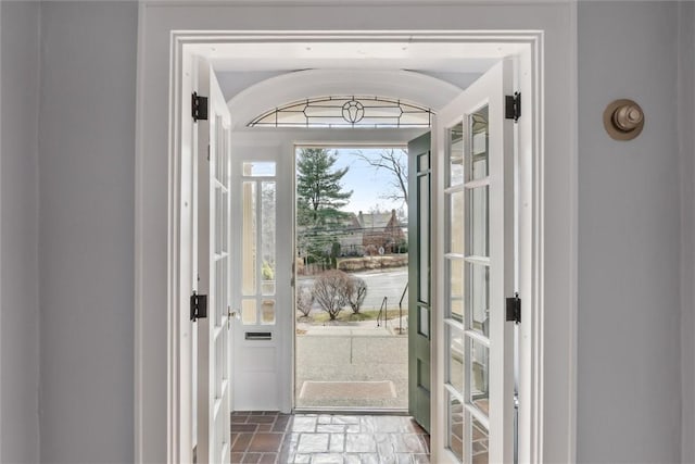 doorway to outside with stone finish flooring and vaulted ceiling