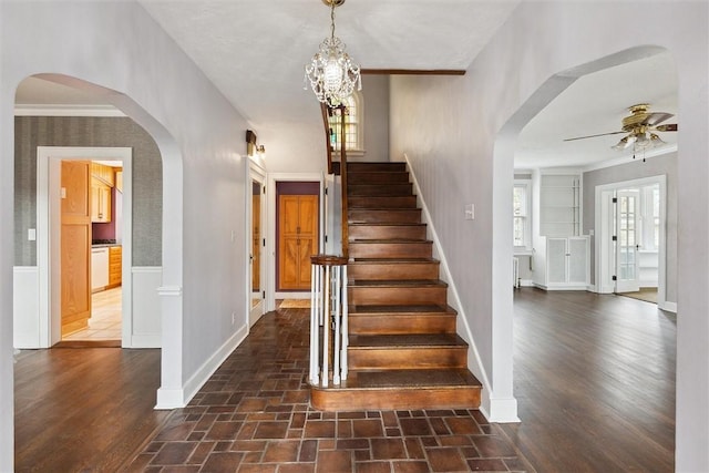 stairs with baseboards, crown molding, ceiling fan, and wood finished floors