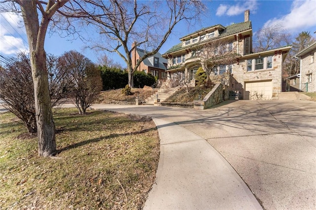 traditional style home with driveway, a chimney, stone siding, a garage, and a tiled roof