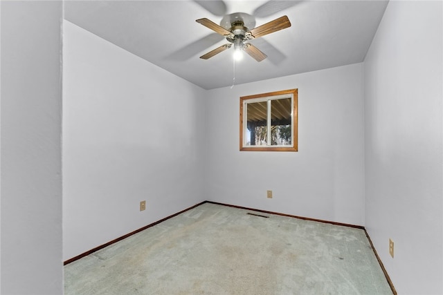 carpeted empty room featuring visible vents, a ceiling fan, and baseboards