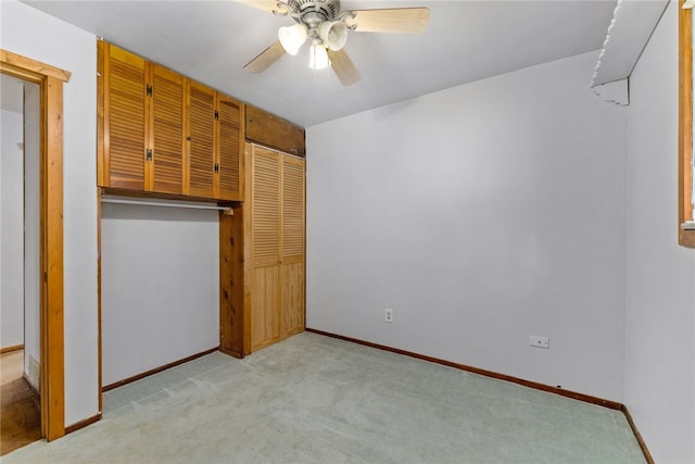 unfurnished bedroom featuring a closet, light colored carpet, ceiling fan, and baseboards