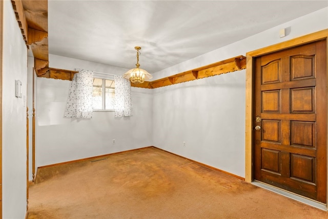 unfurnished room featuring an inviting chandelier, carpet, visible vents, and baseboards