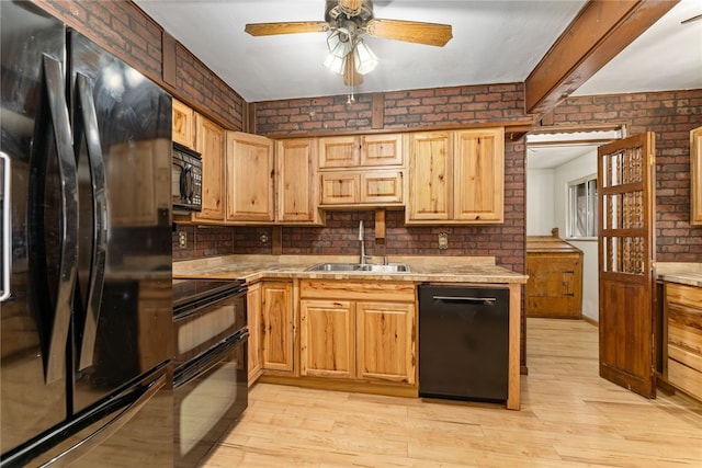 kitchen with brick wall, a sink, light wood finished floors, and black appliances