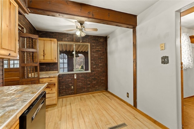 kitchen with brick wall, light wood finished floors, light countertops, and dishwashing machine