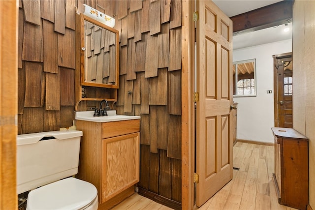 bathroom featuring baseboards, vanity, toilet, and wood finished floors