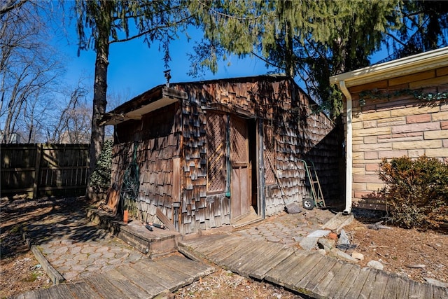 view of outdoor structure featuring fence and an outbuilding