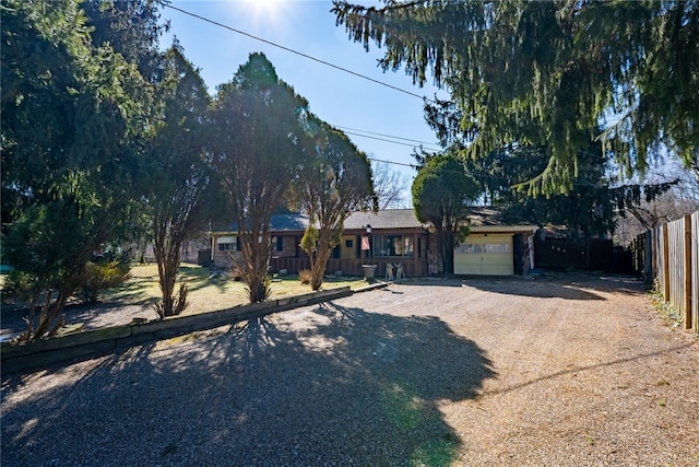 ranch-style house featuring driveway, an attached garage, and fence