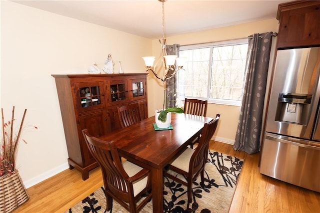 dining space with an inviting chandelier, light wood-style flooring, and baseboards