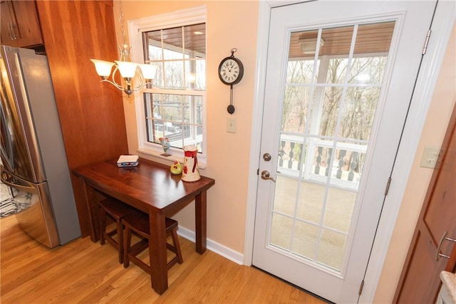 entryway featuring light wood-style floors, plenty of natural light, baseboards, and an inviting chandelier