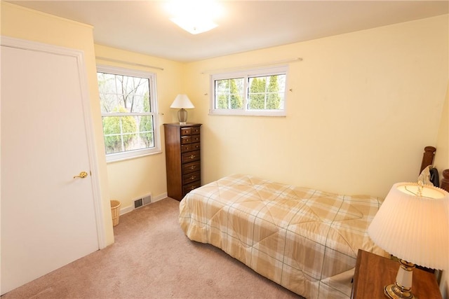 bedroom featuring light carpet, multiple windows, and visible vents