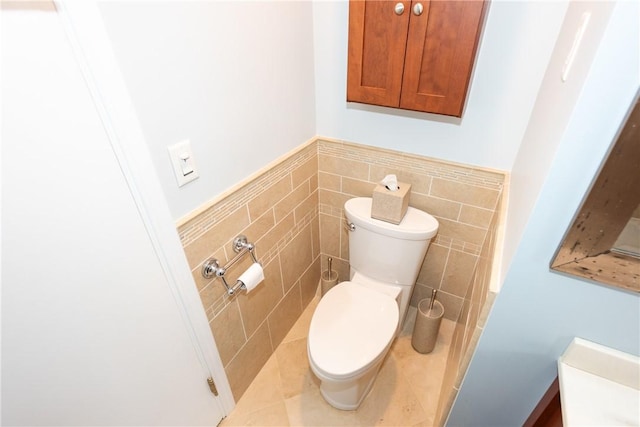 bathroom with toilet, a wainscoted wall, and tile walls