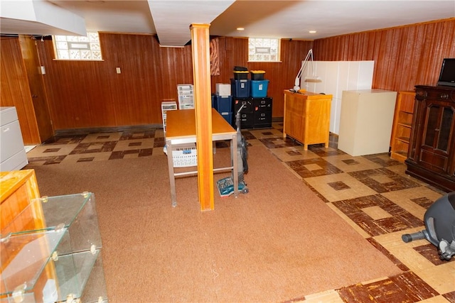 basement featuring a healthy amount of sunlight, wood walls, and tile patterned floors