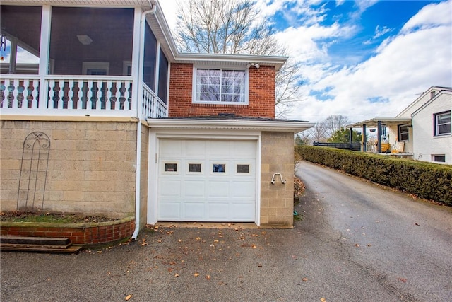 view of side of property with a garage, aphalt driveway, and brick siding