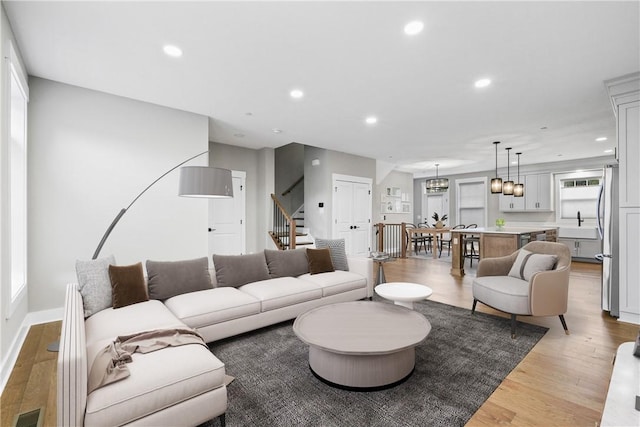 living area with recessed lighting, visible vents, baseboards, stairway, and light wood finished floors