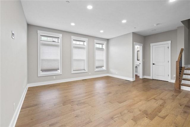 unfurnished room featuring stairway, recessed lighting, wood finished floors, and a healthy amount of sunlight