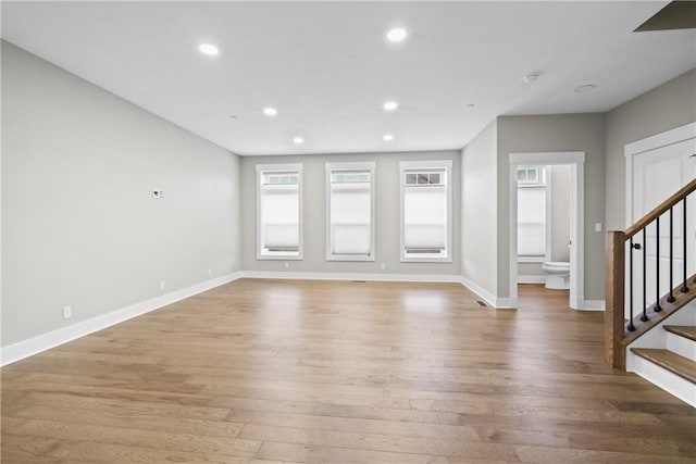 unfurnished living room featuring light wood-style flooring, stairway, baseboards, and recessed lighting