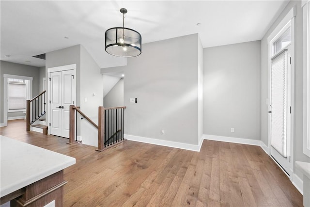 interior space with a chandelier, light wood-style flooring, and baseboards