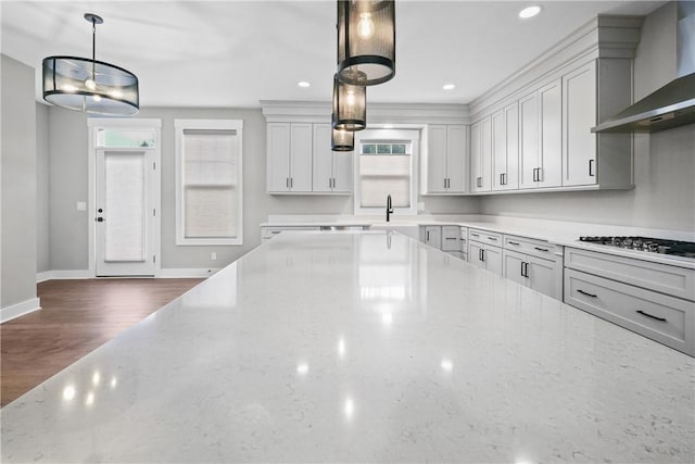 kitchen featuring light stone counters, dark wood finished floors, gas stovetop, a sink, and wall chimney range hood