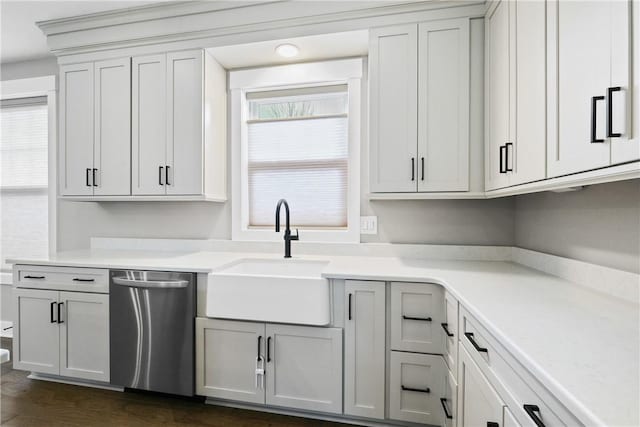 kitchen with a sink, dark wood-style floors, light countertops, and stainless steel dishwasher