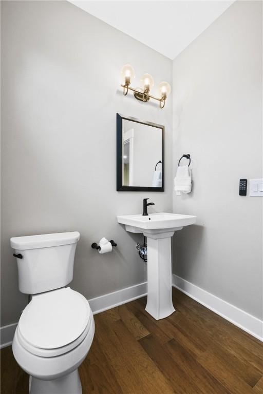 bathroom featuring toilet, a sink, baseboards, and wood finished floors