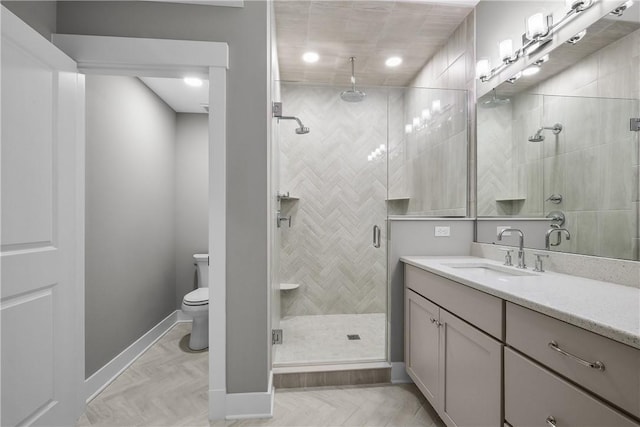 full bathroom featuring vanity, a shower stall, toilet, and baseboards