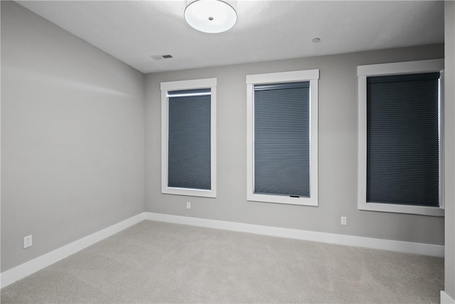 spare room featuring carpet flooring, visible vents, and baseboards