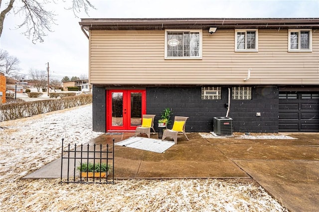 back of property with a garage, french doors, central AC, and concrete driveway