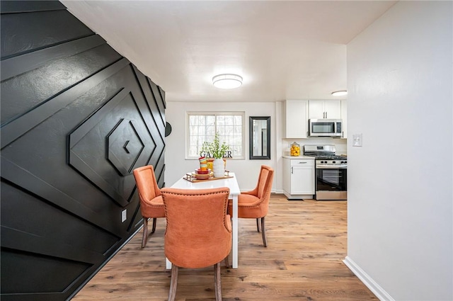 dining space featuring light wood-type flooring and baseboards