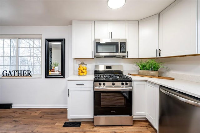 kitchen featuring stainless steel appliances, light countertops, visible vents, and white cabinetry