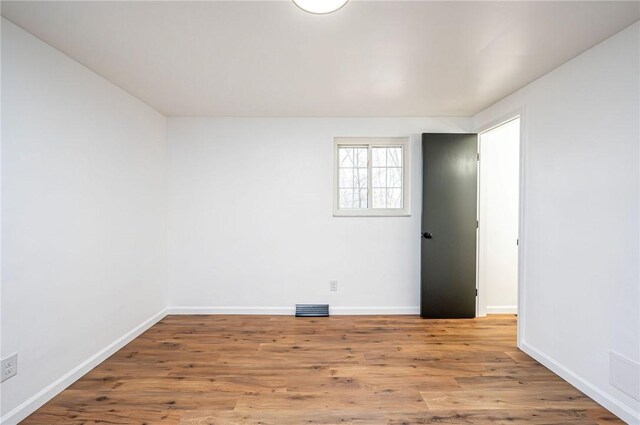 empty room with visible vents, baseboards, and wood finished floors