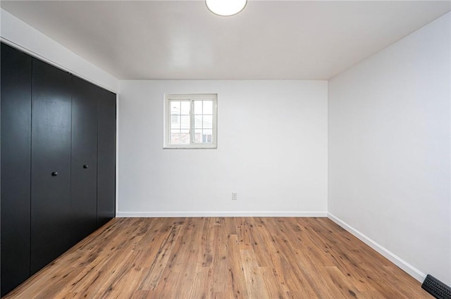 unfurnished bedroom with light wood finished floors, visible vents, baseboards, and a closet