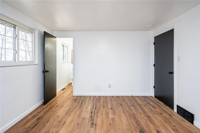 unfurnished room featuring visible vents, baseboards, and wood finished floors