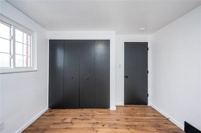 unfurnished bedroom with baseboards, a closet, and light wood-style floors