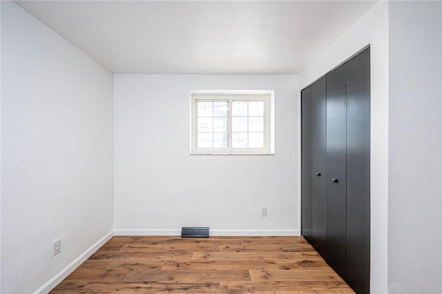 unfurnished bedroom with a closet, baseboards, and wood finished floors