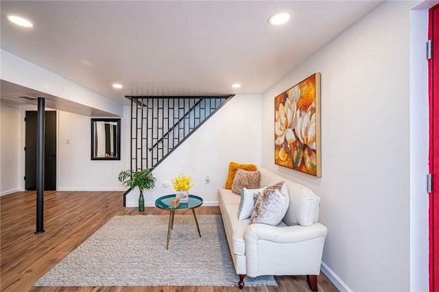 living area with recessed lighting, wood finished floors, baseboards, and stairs