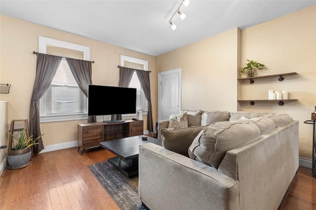 living area with track lighting, wood-type flooring, and baseboards