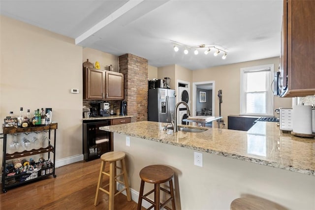 kitchen featuring decorative backsplash, wine cooler, a peninsula, stainless steel refrigerator with ice dispenser, and a sink