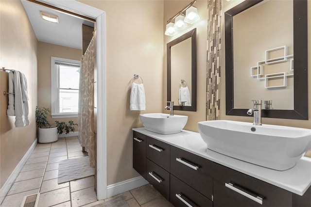 bathroom featuring double vanity, a sink, visible vents, and baseboards